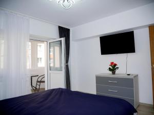 Schlafzimmer mit einem Bett und einer Kommode mit einem TV in der Unterkunft Apartament David in Câmpulung Moldovenesc