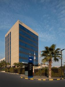 a large building with a palm tree in front of it at DDK Hotel Duhok in Duhok