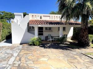 Casa blanca con una palmera y un patio en Alojamiento Chalet en Piriápolis., en Piriápolis