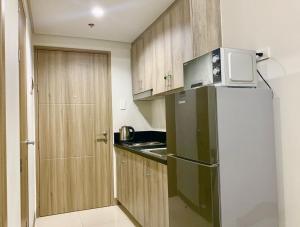 a small kitchen with a refrigerator and a microwave at Sea Residences, S, Shell Janine's Residency in Manila