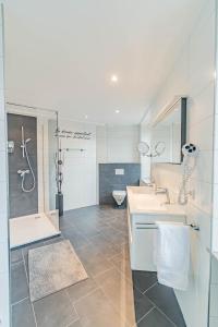 uma casa de banho com 2 lavatórios, um chuveiro e um WC. em Hotel Herckmans em Ettelbruck