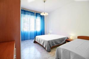 1 Schlafzimmer mit 2 Betten und einem Fenster mit blauen Vorhängen in der Unterkunft Via Brunenghi 63 in Finale Ligure