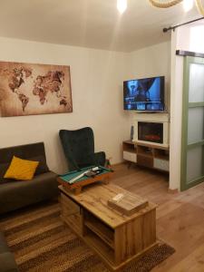ein Wohnzimmer mit einem Sofa, einem Tisch und einem TV in der Unterkunft Maison du Bonheur 2 à TROYES Logement entier avec parking in Troyes