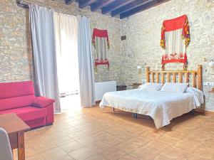 1 dormitorio con 1 cama y 1 sofá rojo en Casa Sara, en Cantavieja