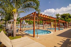 a swimming pool with a pavilion next to a palm tree at Diroma Resort com um dia no Acqua Park in Caldas Novas