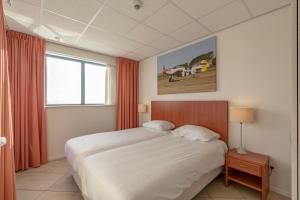 Un dormitorio con una cama grande y una ventana en De Vlijt First class A suite, en De Cocksdorp