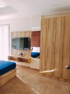 a bedroom with wooden cabinets and a flat screen tv at C V Inn in Baga