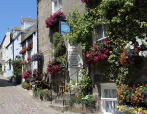 une rue fleurie sur le côté d'un bâtiment dans l'établissement Grey Mullet Guest House, à St Ives