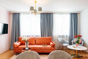 a living room with an orange couch and chairs at Crystal House II - LoftAffair Collection in Kraków