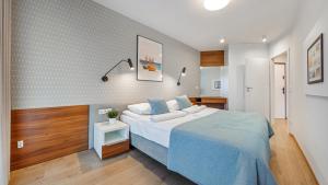 - une chambre avec un grand lit et une couverture bleue dans l'établissement Apartamenty Sun & Snow Na Klifie, à Władysławowo