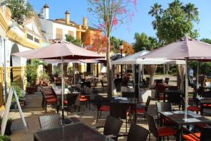 een openluchtrestaurant met tafels, stoelen en parasols bij Nueva Alcaidesa 2104 - Sea Sun and Green in San Roque