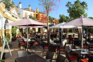 an outdoor restaurant with tables and chairs and umbrellas at Nueva Alcaidesa 2104 - Sea Sun and Green in San Roque