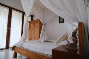 1 dormitorio con 1 cama blanca con dosel en Retreat Villa Toraja Baturinggit, en Kubu