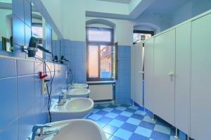 eine Reihe von Waschbecken in einem Bad mit blauen Fliesen in der Unterkunft Hostel Mondpalast in Dresden
