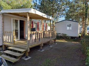 une petite maison avec une terrasse couverte et des escaliers. dans l'établissement mobile home 477 Bois Dormant camping 4*, à Saint-Jean-de-Monts