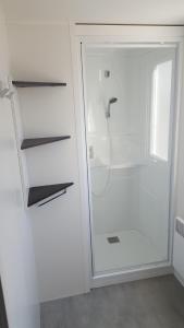 La salle de bains est pourvue d'une douche blanche avec une porte en verre. dans l'établissement mobile home 477 Bois Dormant camping 4*, à Saint-Jean-de-Monts