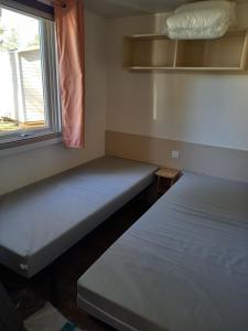 2 camas en una habitación pequeña con ventana en mobile home 477 Bois Dormant camping 4* en Saint-Jean-de-Monts