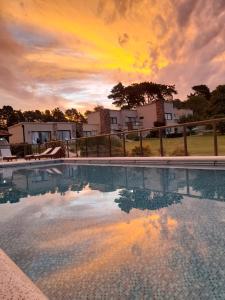 a large swimming pool with a sunset in the background at Chacras de Sierra in Sierra de los Padres