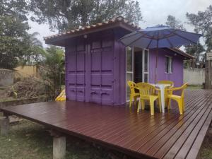 uma casa roxa com duas cadeiras e um guarda-sol num deque em Kitnet contêiner climatizada em Ubatuba
