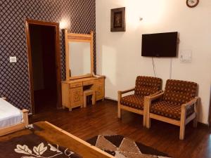 a bedroom with a bed and two chairs and a mirror at Alaf Laila Guest House in Abbottābād