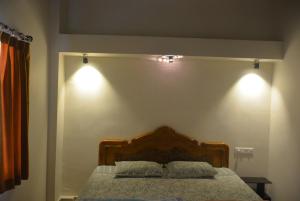 a bedroom with a bed with two lights on the wall at Malaiya Homestay - Grandeur Living Experience in Jabalpur