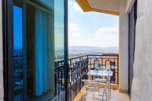 a balcony with a table and chairs and a view at Tropical Plaza Apartments in Kigali