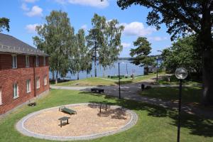 a park next to a brick building and the water at Vår Gård Saltsjöbaden in Saltsjöbaden