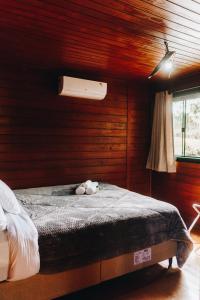 a bedroom with a bed with a stuffed animal on it at Chalé Aconchego - Pousada Cachoeira da Neve in Urubici