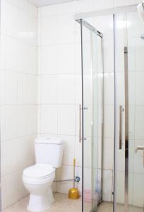 a bathroom with a toilet and a glass shower at Tropical Plaza Apartments in Kigali