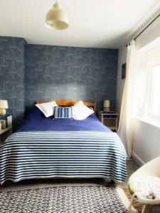 a bedroom with a bed with a blue wall at Odun Terrace in Appledore