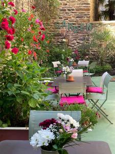 une table et des chaises dans un jardin fleuri dans l'établissement Garden Hotel Rennes Centre Gare, à Rennes