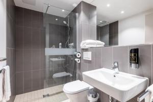 a bathroom with a sink and a toilet and a mirror at Serways Hotel Hösel in Ratingen