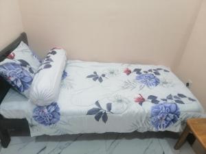 a bed with a white blanket with flowers on it at Zulcity Homestay in Gelugor