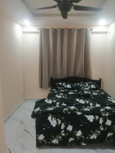 a bedroom with a bed with a black blanket with white flowers at Zulcity Homestay in Gelugor