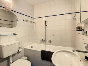 een badkamer met een wastafel, een toilet en een bad bij Porthos 29-30 in Verbier