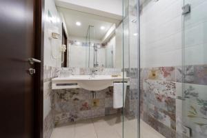 bagno con lavandino e doccia in vetro di Hotel Olanesti & Spa Medical a Băile Olăneşti