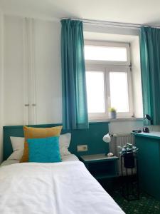 a bedroom with a bed with blue curtains and a window at Hotel am Friedberger See in Friedberg