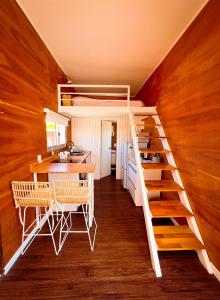 Habitación con cama elevada, mesa y cocina en Tiny House Aire en La Juanita en José Ignacio