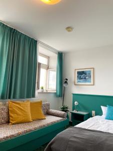 a bedroom with green curtains and a bed with yellow pillows at Hotel am Friedberger See in Friedberg