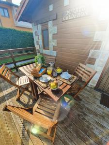 a picnic table with two chairs and food on a deck at Apartamentos & Bungalows Ubiarco El Acebo by Alterhome in Ubiarco