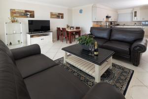 una sala de estar con 2 sofás negros y una mesa. en Main Beach Penthouse, en Jeffreys Bay