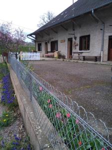 a fence in front of a house with pink flowers at chez Domi Syl gite nature in Colonne