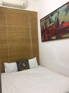 Un dormitorio con una cama blanca con una foto en la pared en Melody home, en Hanói
