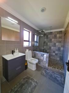 ein Bad mit einem Waschbecken, einem WC und einer Dusche in der Unterkunft LAKE-HOUSE CABIN in Witbank