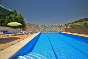 a swimming pool with two chairs and an umbrella at Finca La Rana Verde in Cortes de la Frontera