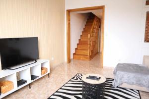 un salon avec une télévision à écran plat et un escalier dans l'établissement Sunset House, à Ribeira Brava