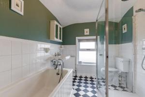 a bathroom with a tub and a toilet and a shower at Lindley Terrace - Norfolk Holiday Properties in Norwich