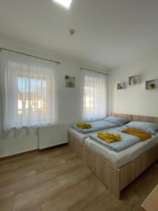 2 camas en un dormitorio con paredes blancas y suelo de madera en Dóra Vendégház, en Csongrád