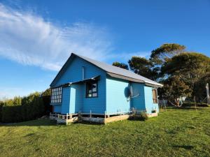 een blauw huis in een veld in een veld bij Cabañas Quetalmahue in Ancud