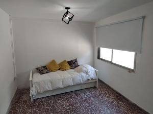 Un dormitorio con una cama con almohadas amarillas y una ventana en Cómoda casa en El Volcan en San Luis